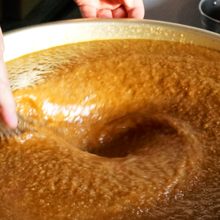 醤油ベースでニンニクのパンチが効いた　秘伝のからあげ漬け込みダレを大きな樽で混ぜている